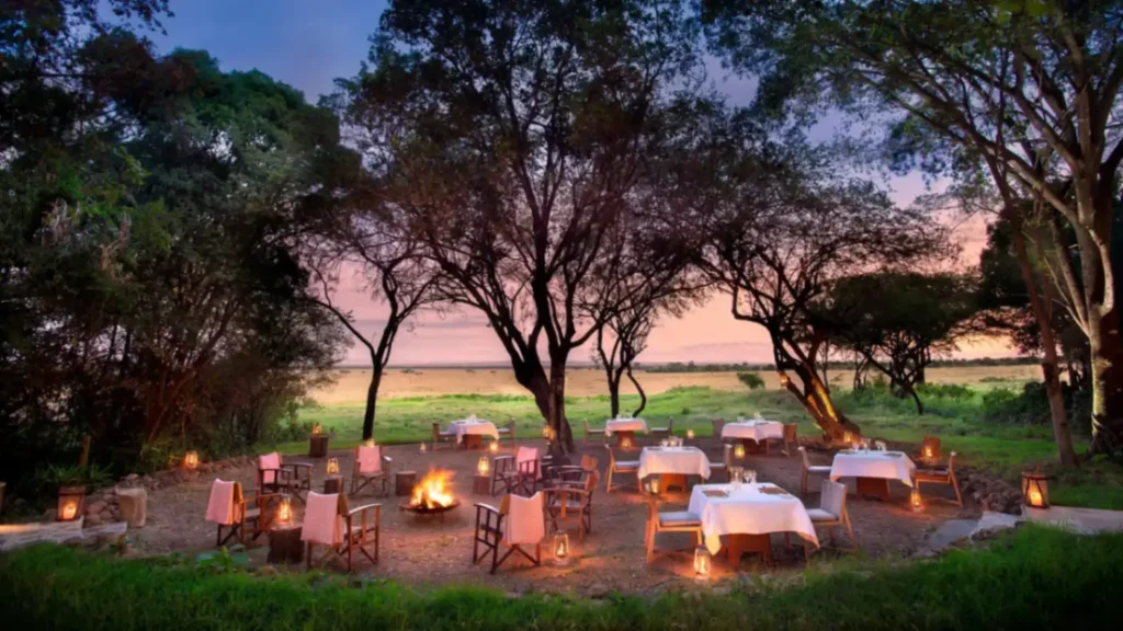 Guests gathered around a bonfire at &Beyond Bateleur Camp in the Masai Mara, Kenya.
