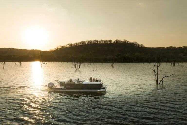 Guests enjoying a sunset cruise at Singita Pamushana Lodge overlooking Malilangwe Dam in Gonarezhou, Zimbabwe