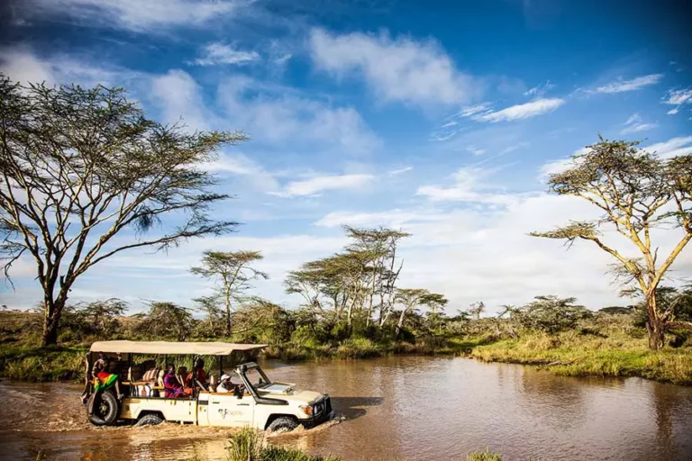 Thrilling game drive in East Africa with a safari jeep crossing a river