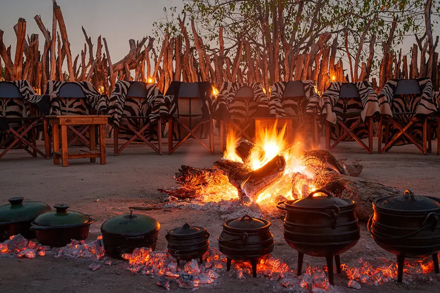 Guests gathered around a traditional boma fire at Jao Camp in the Okavango Delta, Botswana during an evening safari experience