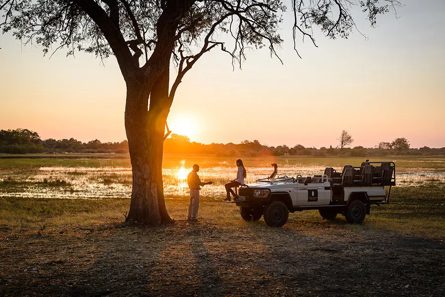 Guests enjoying sundowners at Sanctuary Chief's Camp while watching the sunset over the Okavango Delta floodplains in Botswana.